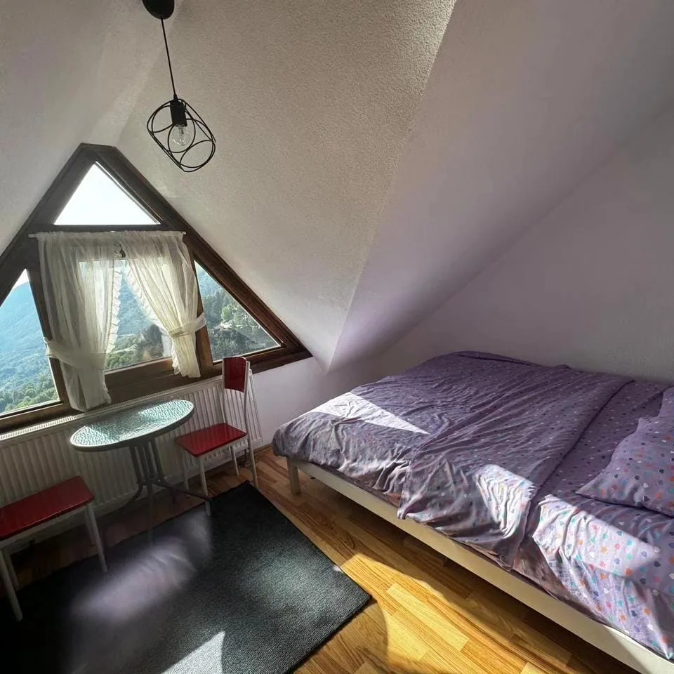 Attic bedroom with triangular window in Apartment 3 at Villa Bjeshka